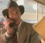 Reklamfiguren Harry Hotline med hatt och mobiltelefon av 1990 års modell (stor).