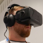 Man iförd Oculus Rift. Hörlurar och en svart låda framför ögonen.